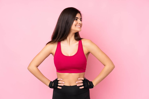Young sport woman over isolated pink background posing with arms at hip and looking side - Foto, afbeelding
