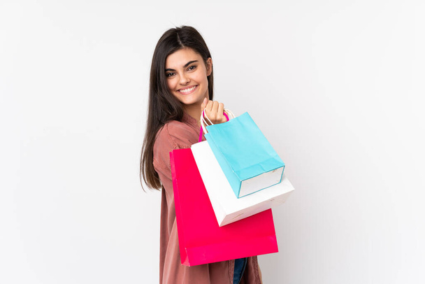 Jonge vrouw over geïsoleerde witte achtergrond houden boodschappentassen en glimlachen - Foto, afbeelding