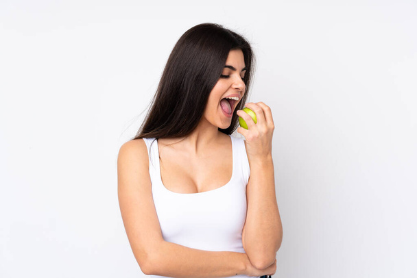 Молодая женщина на изолированном белом фоне ест яблоко - Фото, изображение