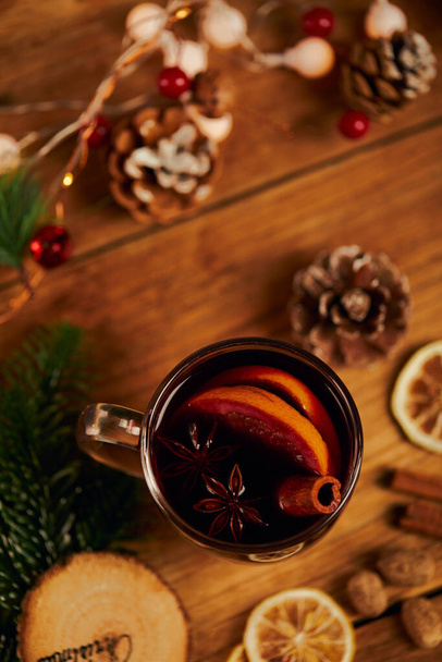 A cup of hot tea with citrus and cinnamon on wooden table with dried lemon slices and Christmas decors - 写真・画像