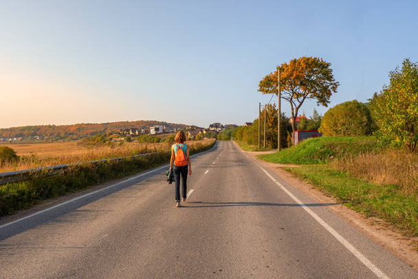 Samostatný koncept cesty. Zadní pohled na ženu s batohem chůze na podzim země silnici, pěší výlet. - Fotografie, Obrázek