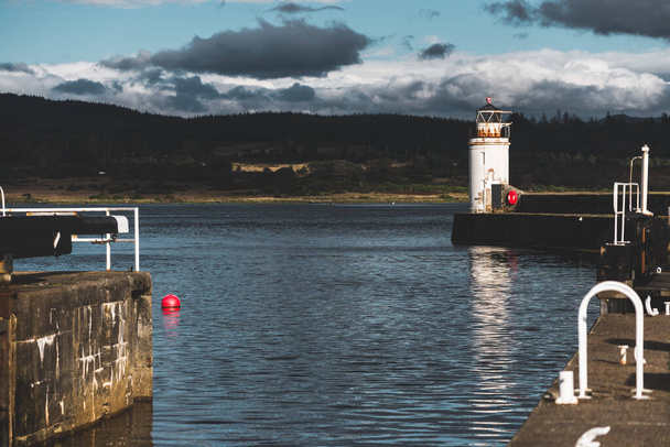 Une promenade vide vers le vieux phare, gros plan. Des rivages rocheux en arrière-plan. Paysage nuageux dramatique. Ardrishaig, canal de Crinan, Écosse, Royaume-Uni. Destinations touristiques, thème touristique - Photo, image