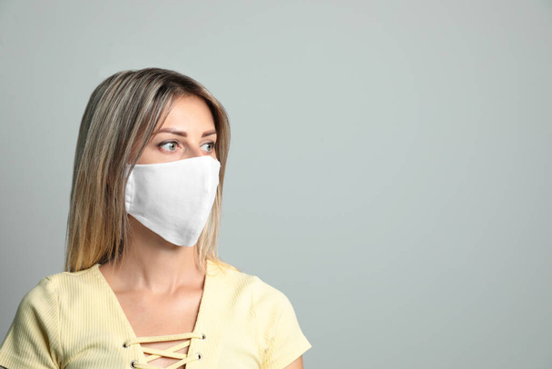 Young woman in protective face mask on light grey background. Space for text - Φωτογραφία, εικόνα