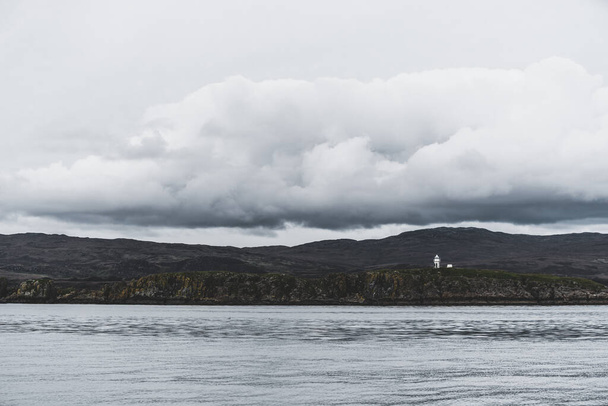 Blick auf das felsige Ufer in der Nähe der Gipfel des Paps of Jura unter wolkenlosem blauem Himmel. Ein Blick von der Jacht. Jura-Insel, Innere Hebriden, Schottland, Großbritannien. Reiseziele, Sehenswürdigkeiten - Foto, Bild