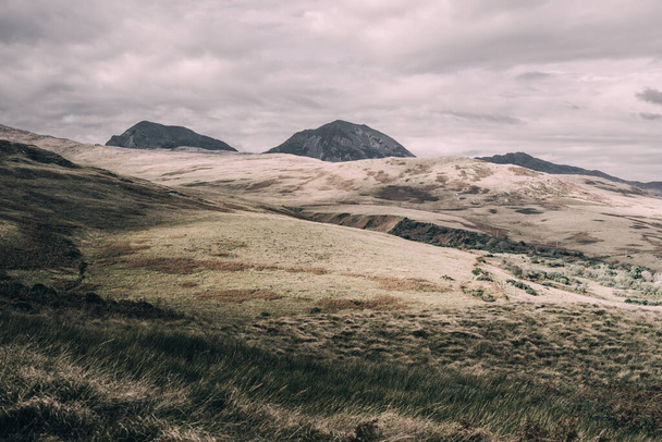 Panoramiczny widok na dolinę w pobliżu najwyższego szczytu góry Paps of Jura (Beinn ir) pod ciemnym burzowym niebem. Dramatyczne chmury. Wyspa Jura, Hebrydy Wewnętrzne, Szkocja, Wielka Brytania. Krajobraz atmosferyczny. - Zdjęcie, obraz