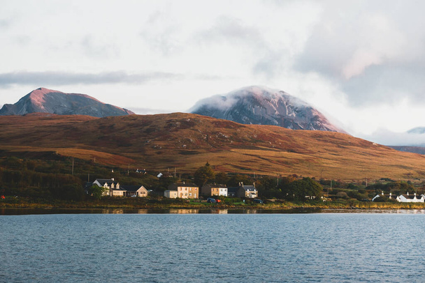 Panoramic view of the valley near the Paps of Jura under the colorful stormy sunset sky. Traditional country houses close-up. Dramatic cloudscape. Craighouse, Jura island, Inner Hebrides, Scotland, UK - Fotó, kép