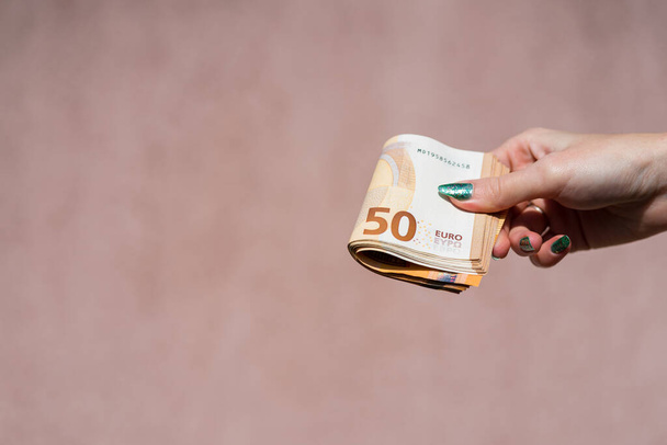 Hand holding showing euro money and giving or receiving money like tips, salary. 50 EURO banknotes EUR currency isolated. Concept of rich business people, saving or spending money. - 写真・画像