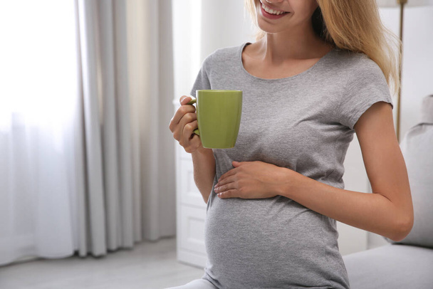 Beautiful pregnant woman drinking tea at home, closeup - Fotoğraf, Görsel