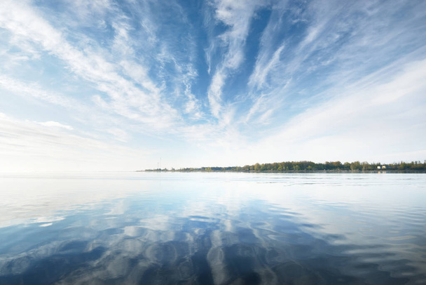 Балтийское море после дождя на закате. Драматическое голубое небо с перистыми облаками, симметричные отражения в воде. Абстрактный узор, текстура, фон, концепт-арт - Фото, изображение