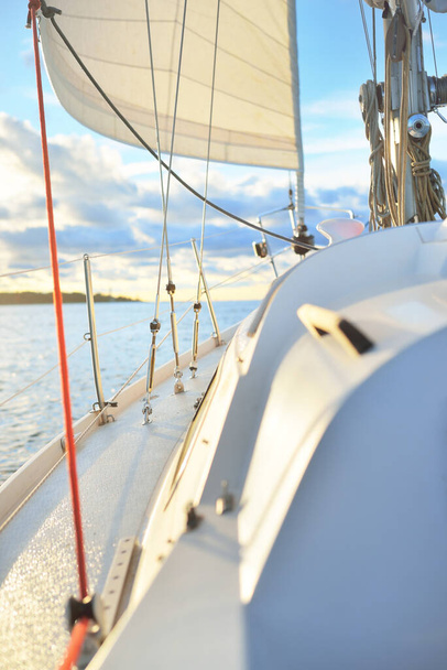 Bílá jachta plující po dešti při západu slunce. Pohled zblízka z paluby na příď. Jasná zářící obloha s barevnými zlatými a růžovými mraky. Idylický plášť. Moře, okružní plavba, cestovní destinace - Fotografie, Obrázek