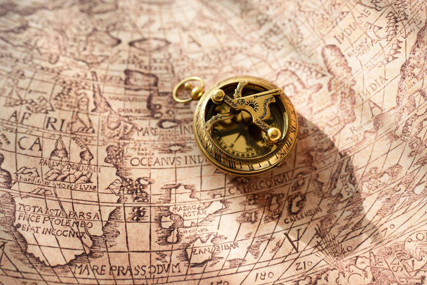 Retro styled golden antique compass (sundial) and old white nautical chart close-up. Vintage still life. Sailing accessories. Travel, navigation concepts, collecting, souvenir, gift, graphic resource - Photo, Image