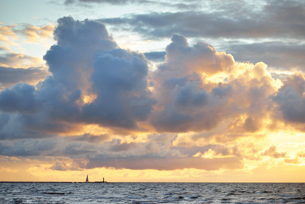 Ciel clair avec beaucoup de nuages de cumulus rose brillant au-dessus de la côte de la mer Baltique après l'orage au coucher du soleil. Paysage nuageux dramatique. Lumière du soleil dorée chaude. Paysage pittoresque. Météo de faucille - Photo, image