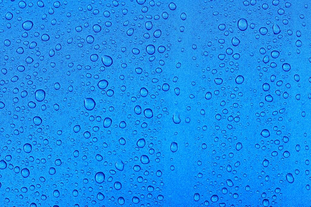 Bright blue background, crystal clear water drops (raindrops). Abstract natural pattern, wallpaper, concept art. Glittering paint texture. Graphic resources, design, 3D, decoration, macro photography - Photo, Image
