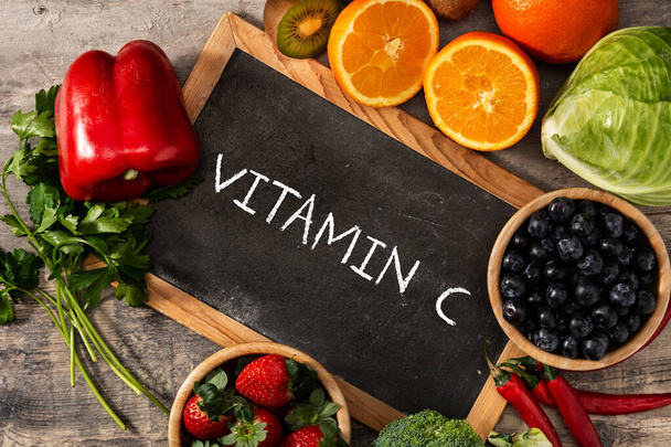 High in vitamin C food and blackboard on wooden table. - Valokuva, kuva