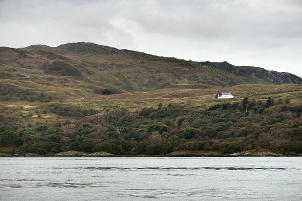 インナーヘブリディーズ諸島の崖、山、谷のパノラマビュー。イギリスのスコットランド。孤独な家のクローズアップ。劇的な空、嵐の雲。自然、旅行先、クルーズ、観光テーマ - 写真・画像