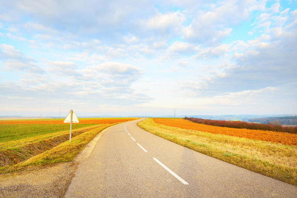Un camino de asfalto vacío (carretera) a través de los campos. Cielo dramático. Francia, Europa. Transporte, logística, destinos turísticos, turismo, conducción, velocidad, libertad, cierre - Foto, imagen