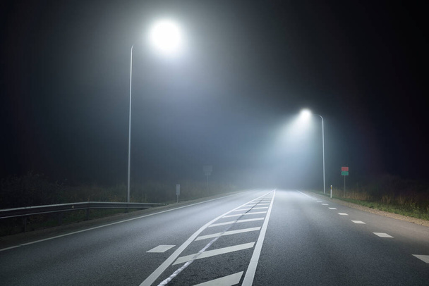 夜には霧の中で、照明された新しい高速道路のパノラマビューを、街路灯を閉じます。ムーンライト。暗い都会の風景。ヨーロッパだ。交通、物流、旅行、観光、道路旅行、自由、運転 - 写真・画像