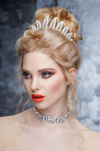 Modeporträt der schönen Frau mit Tiara auf dem Kopf. Elegante Frisur. Perfektes Make-up und Schmuck. Korallenlippen - Foto, Bild