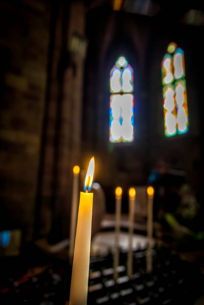 Candles burning in the foreground inside an old church in Spain. Religion, old architecture, Christianity, travel, concept of belief - Photo, Image
