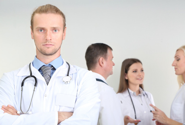 Доктор стоит перед коллегами на сером фоне
 - Фото, изображение