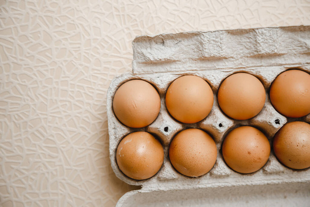 10 huevos de pollo marrón yacen en bandeja de cartón sobre la mesa - Foto, imagen