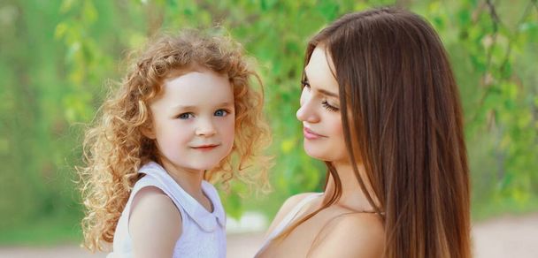 Portrait of happy mother and daughter child together in a sunny summer park - Photo, image