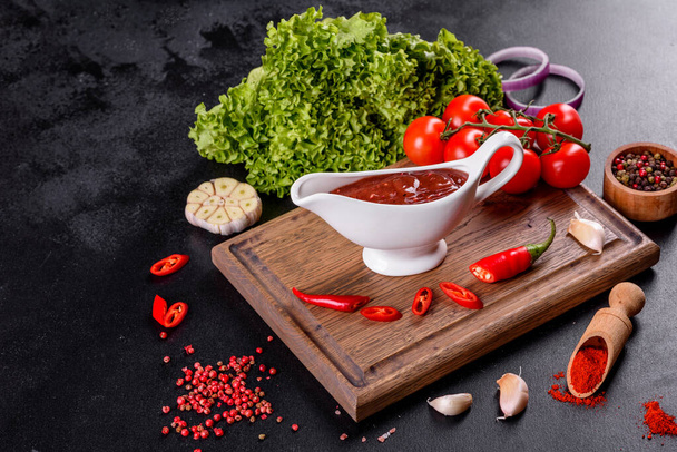 Pikantne przyprawy gruzińskiej kuchni adjika w misce z czerwonym pieprzem i czosnkiem na betonowym stole zbliżenie - Zdjęcie, obraz