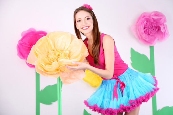 Beautiful young woman in petty skirt holding big flower on decorative background - Zdjęcie, obraz