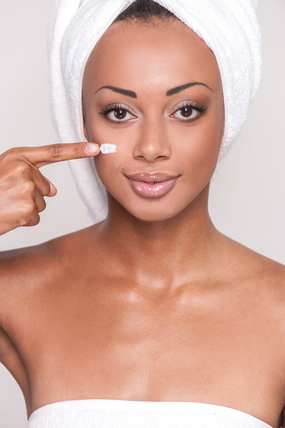 Afro-American woman spreading cream on her face - 写真・画像