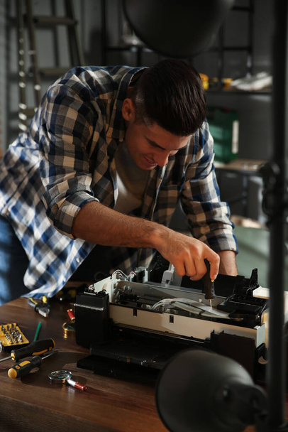 Repairman with screwdriver fixing modern printer in office - Фото, зображення