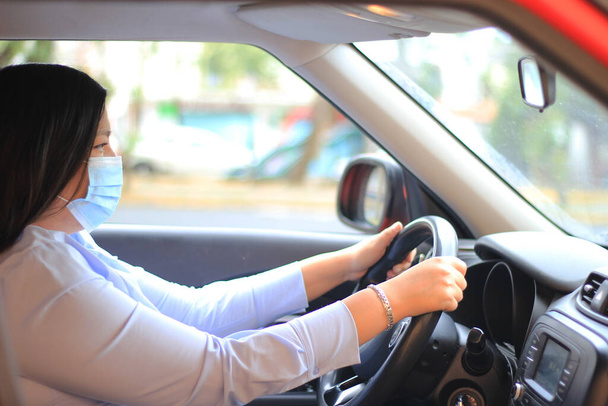 Femme latine conducteur dans l'intérieur de la voiture avec masque de protection utilisation clinique par covid - Photo, image