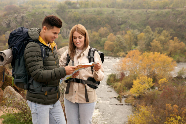 Couple of travelers with backpacks and map planning trip in mountains. Autumn vacation - Foto, Bild