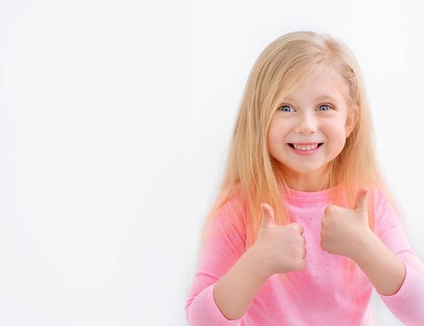 Κοντινό πλάνο πορτρέτο του συμπαθητικού χαριτωμένο χαρούμενο μικρό κορίτσι, δείχνει διπλό αντίχειρες-up - Φωτογραφία, εικόνα