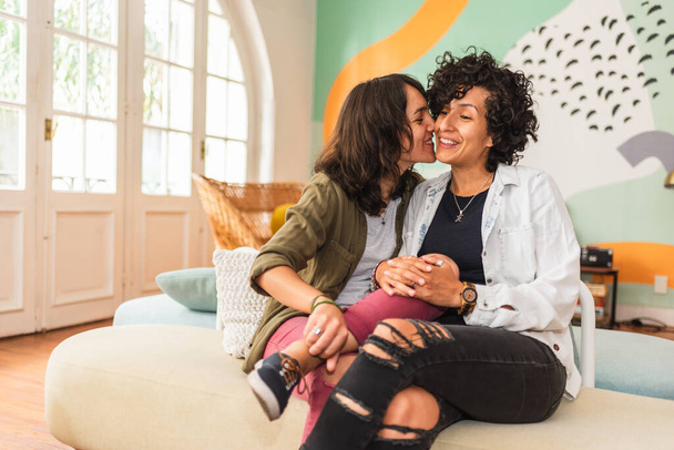 Stock photo of happy couple sitting in their apartment kissing and smiling. - Zdjęcie, obraz