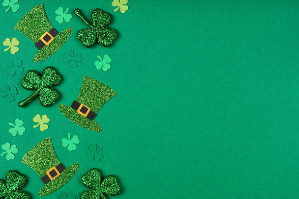 St Patricks Day shamrock and leprechaun hat side border. Top down view over a green paper background with copy space. - Foto, afbeelding