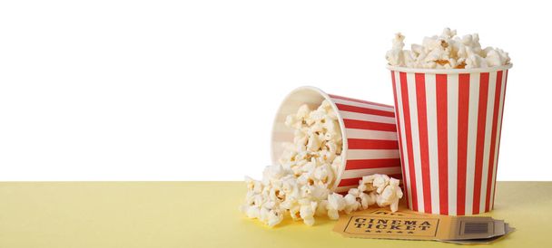 Cups with delicious popcorn and tickets on table against white background - Fotoğraf, Görsel