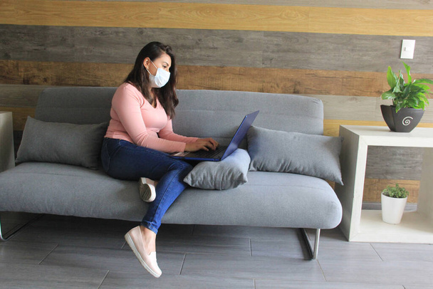Latina woman works at home with protection mask in covid pandemic - Photo, Image
