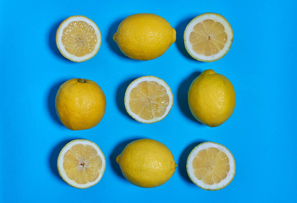 Celé a rozpůlené citróny na modrém pozadí. CITRUS CITRIC - Fotografie, Obrázek