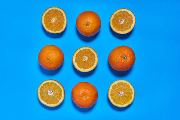 Целые и разделенные апельсины на синем фоне. ЦИТРУС СИТРИК - Фото, изображение