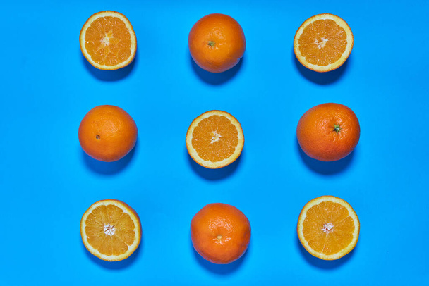 Całe i podzielone pomarańcze na niebieskim tle. CITRUS CITRIC - Zdjęcie, obraz