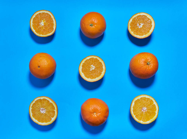 Ολόκληρα και μοιρασμένα πορτοκάλια σε μπλε φόντο. CITRUS CITRIC - Φωτογραφία, εικόνα