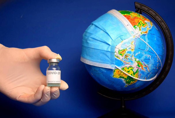 Coronavirus COVID-19 vaccine. against the background of the globe. Doctor holding Corona virus vaccine.  - Fotoğraf, Görsel