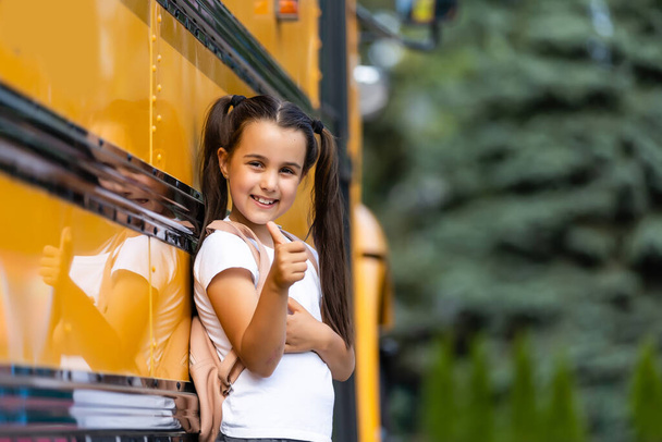 Sarı okul otobüsünün yanında sırt çantalı bir kız. Öğrenciler için taşıma - Fotoğraf, Görsel