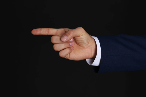 Businessman pointing at something on black background, closeup. Finger gesture - Fotoğraf, Görsel