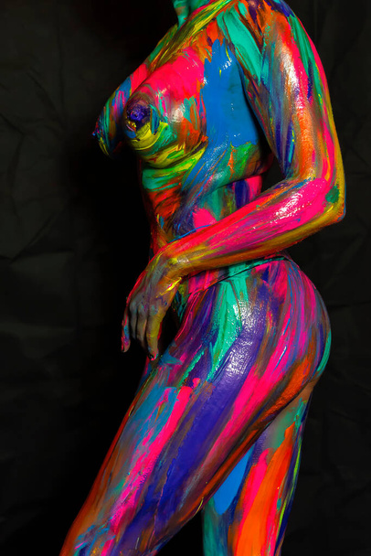 A naked woman is painted with colorful paint in a home environment - Foto, immagini