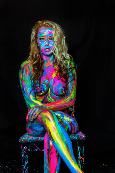 Una donna nuda è dipinta con vernice colorata in un ambiente domestico
 - Foto, immagini