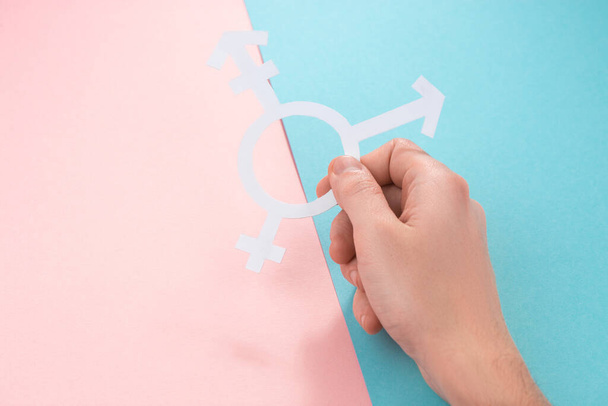 Hand holding a sign of trans people on pink and blue background - 写真・画像
