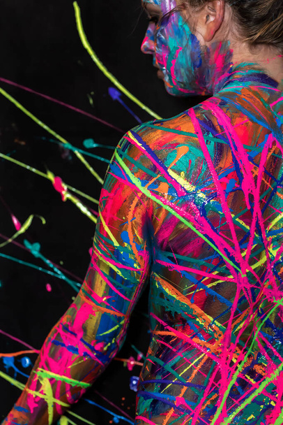 A naked woman is painted with colorful paint in a home environment - Photo, Image