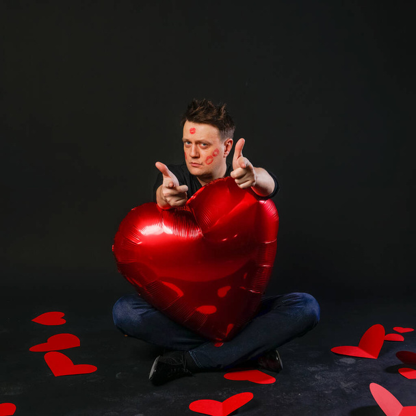 valentines heart red, inflatable balloon in hands, sexy adventure. On a black background background cheerful, romance - Photo, Image