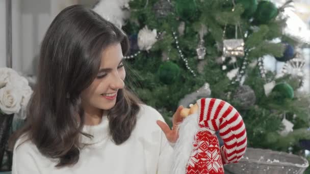 Γοητευτική όμορφη γυναίκα χαμογελώντας στην κάμερα κρατώντας χαριτωμένο παιχνίδι Άγιος Βασίλης - Πλάνα, βίντεο